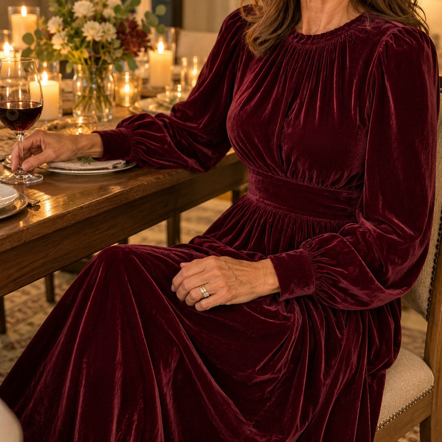 A woman seated at a candlelit dinner in the burgundy Elena